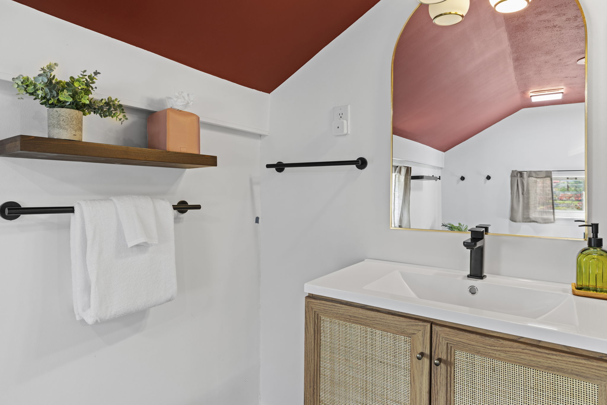 Stylish bathroom with arched mirror, modern vanity, and warm designer touches