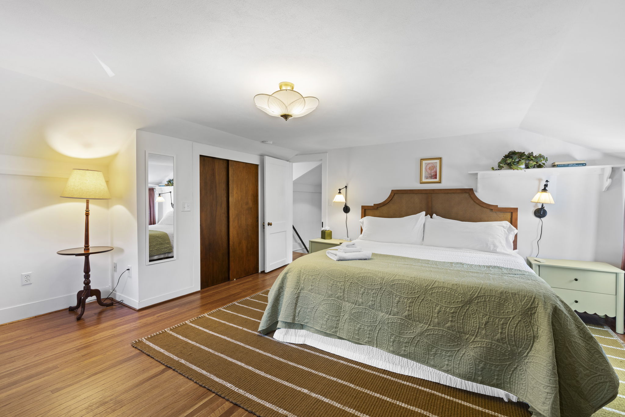 Spacious, serene bedroom with king bed, warm wood floors, and soft lighting