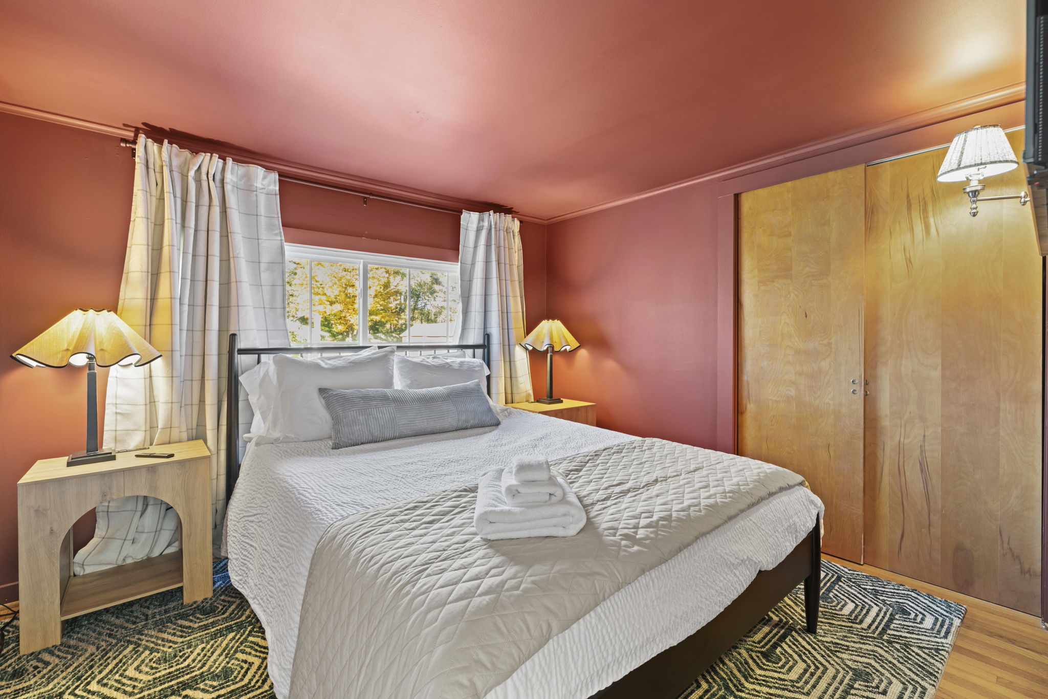 Cozy queen bedroom with warm lighting, natural light, and ample closet space