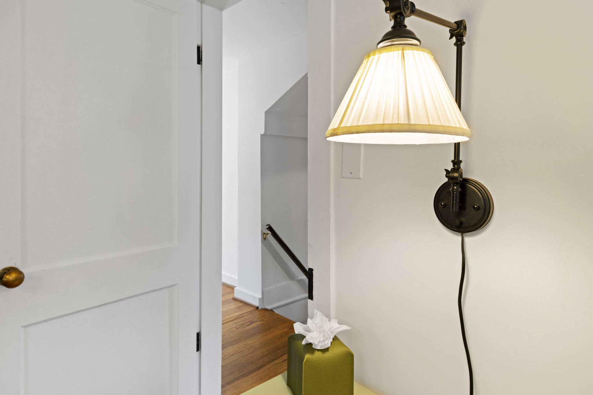 Bright hallway with warm hardwood floors and elegant wall sconce