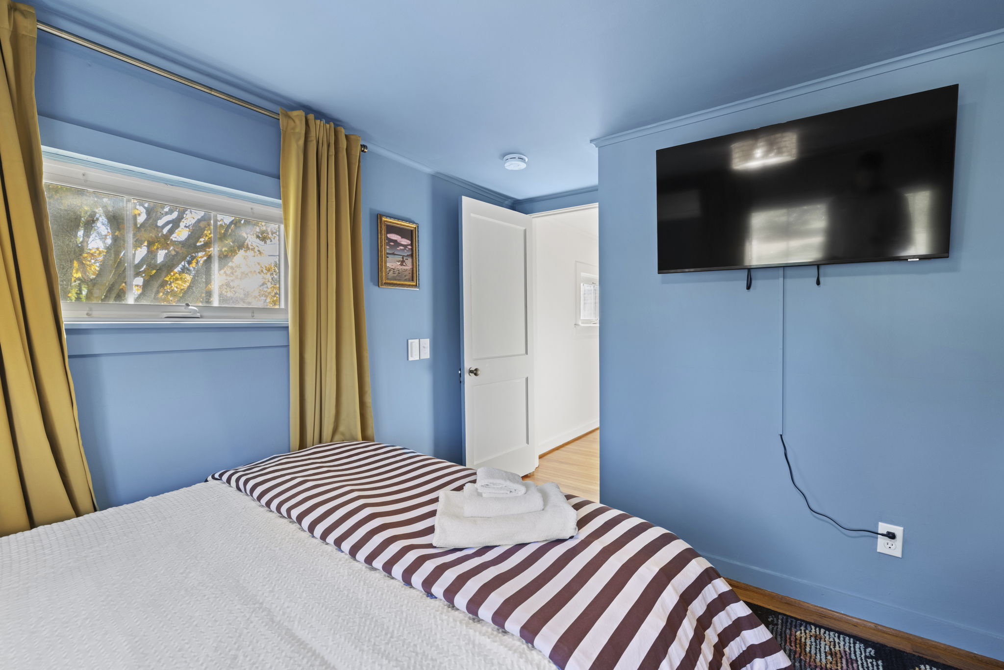 Cozy blue bedroom with natural light, TV, and fresh guest-ready linens