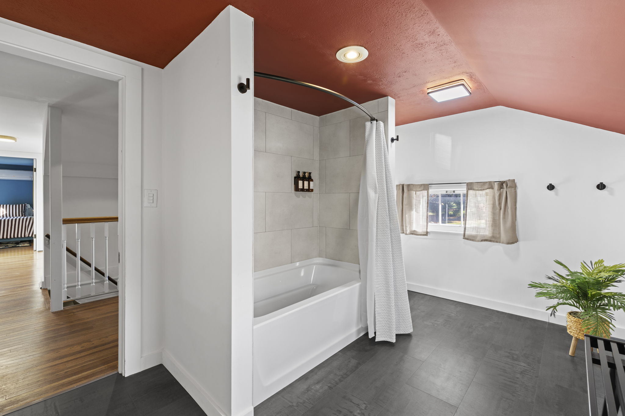 Spacious bathroom with tiled tub, high ceilings, and bright natural light