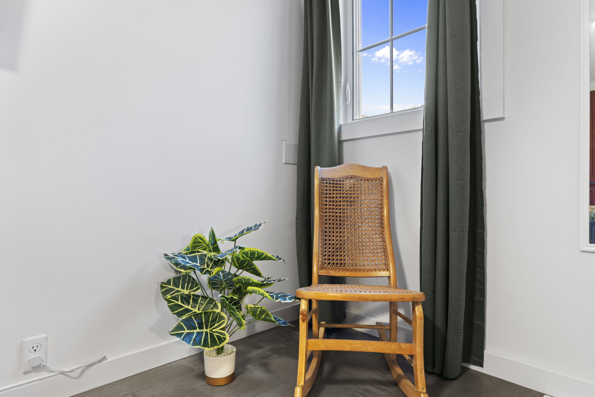 Sunny reading nook with rocking chair, tall window, and fresh greenery
