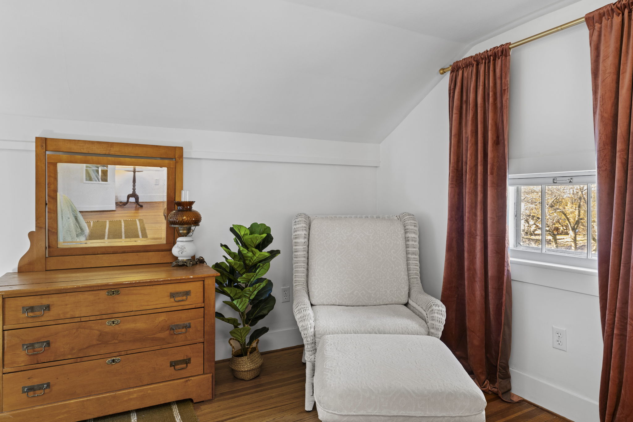Cozy reading nook with vintage dresser, plush chair, and warm natural light