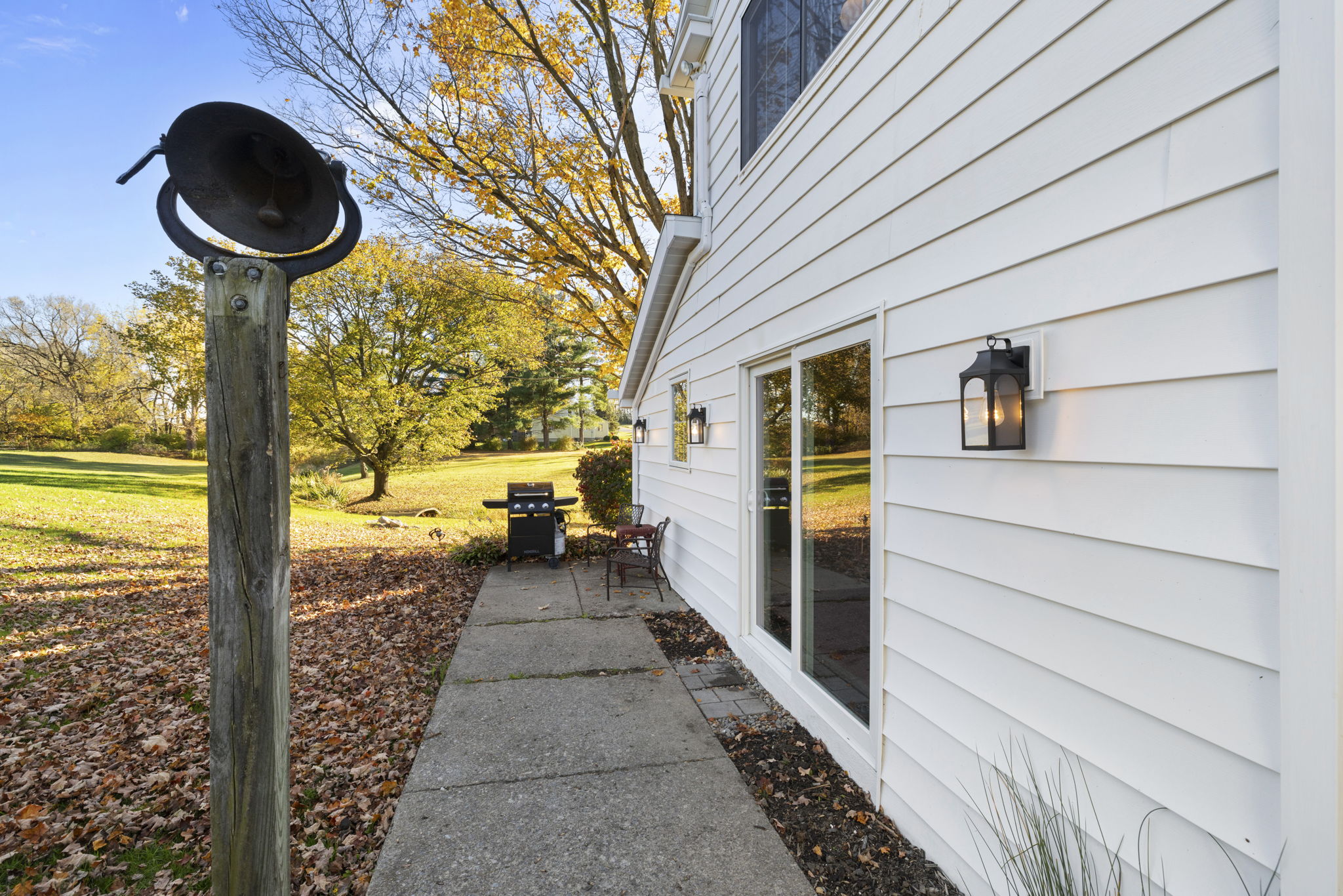 Private patio with grill, seating, and a spacious tree-lined yard
