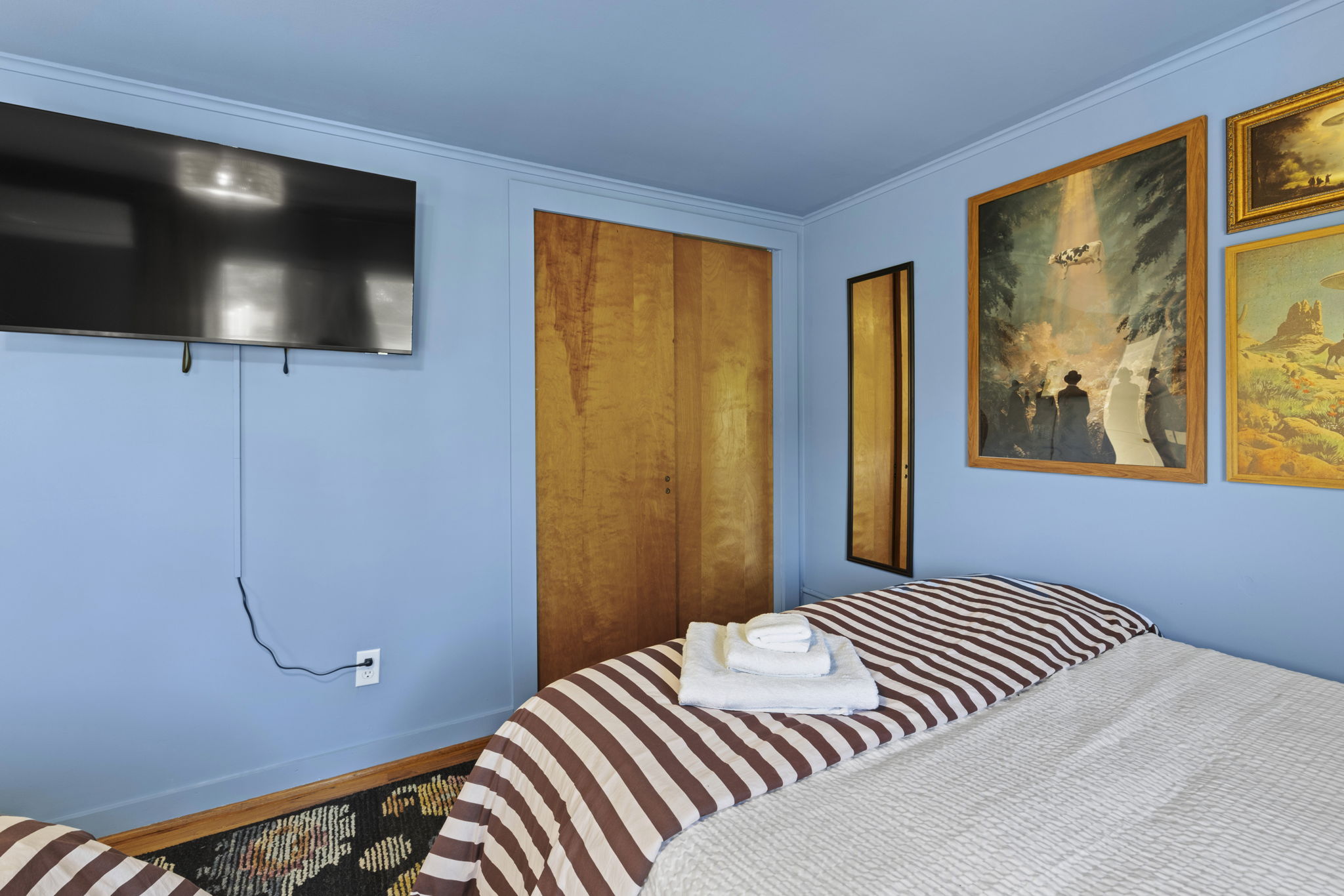 Cozy bedroom with wall-mounted TV, warm wood accents, and stylish art