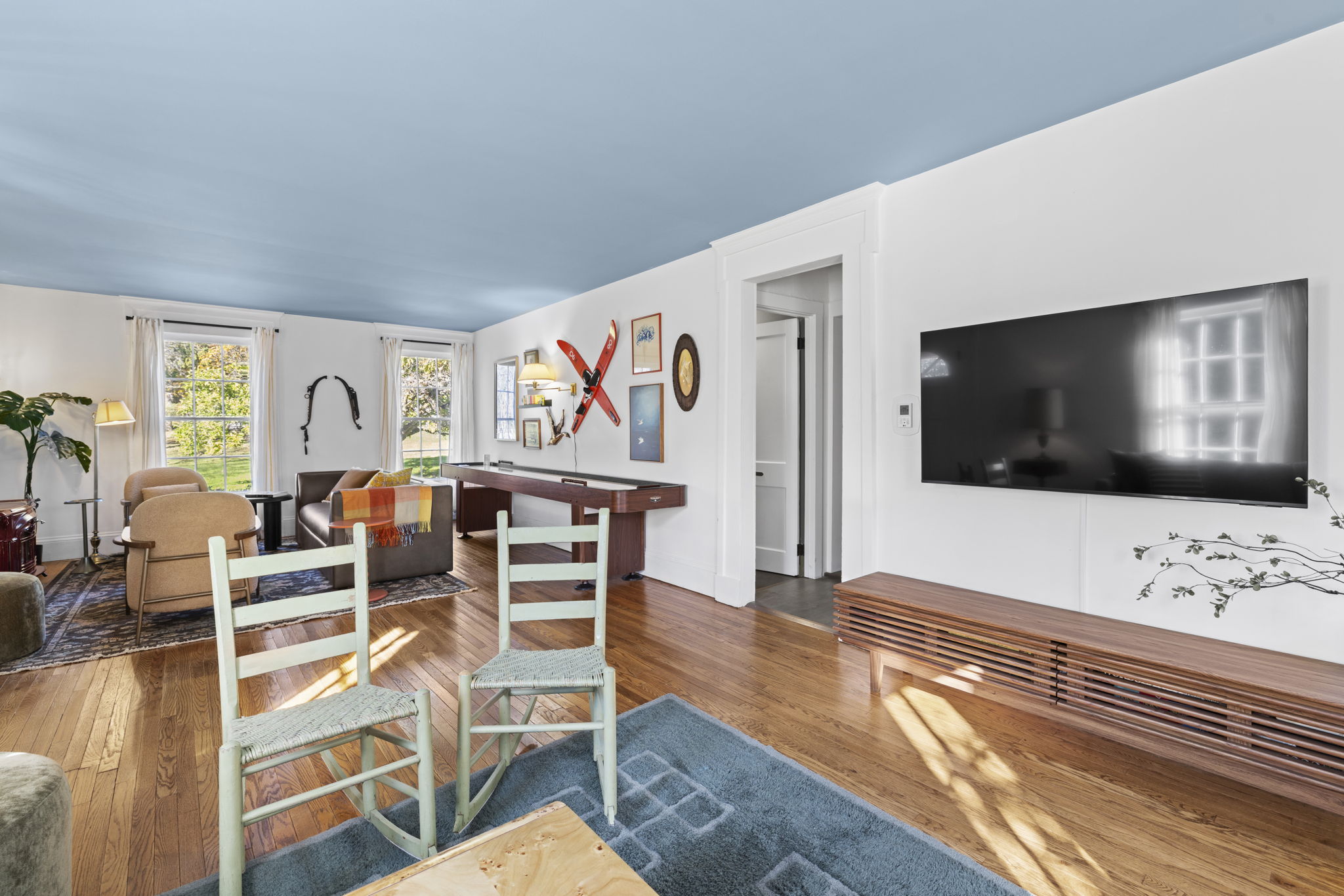 Bright, spacious living room with large TV, hardwood floors, and sunny windows