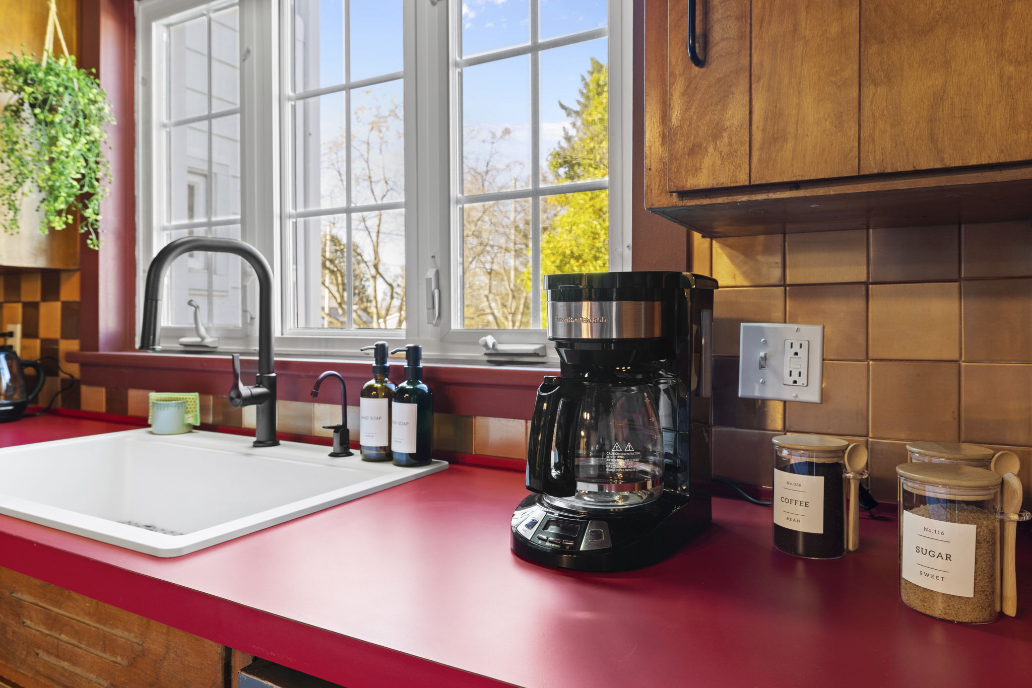 Sunny kitchen with farmhouse sink, coffee station, and garden views