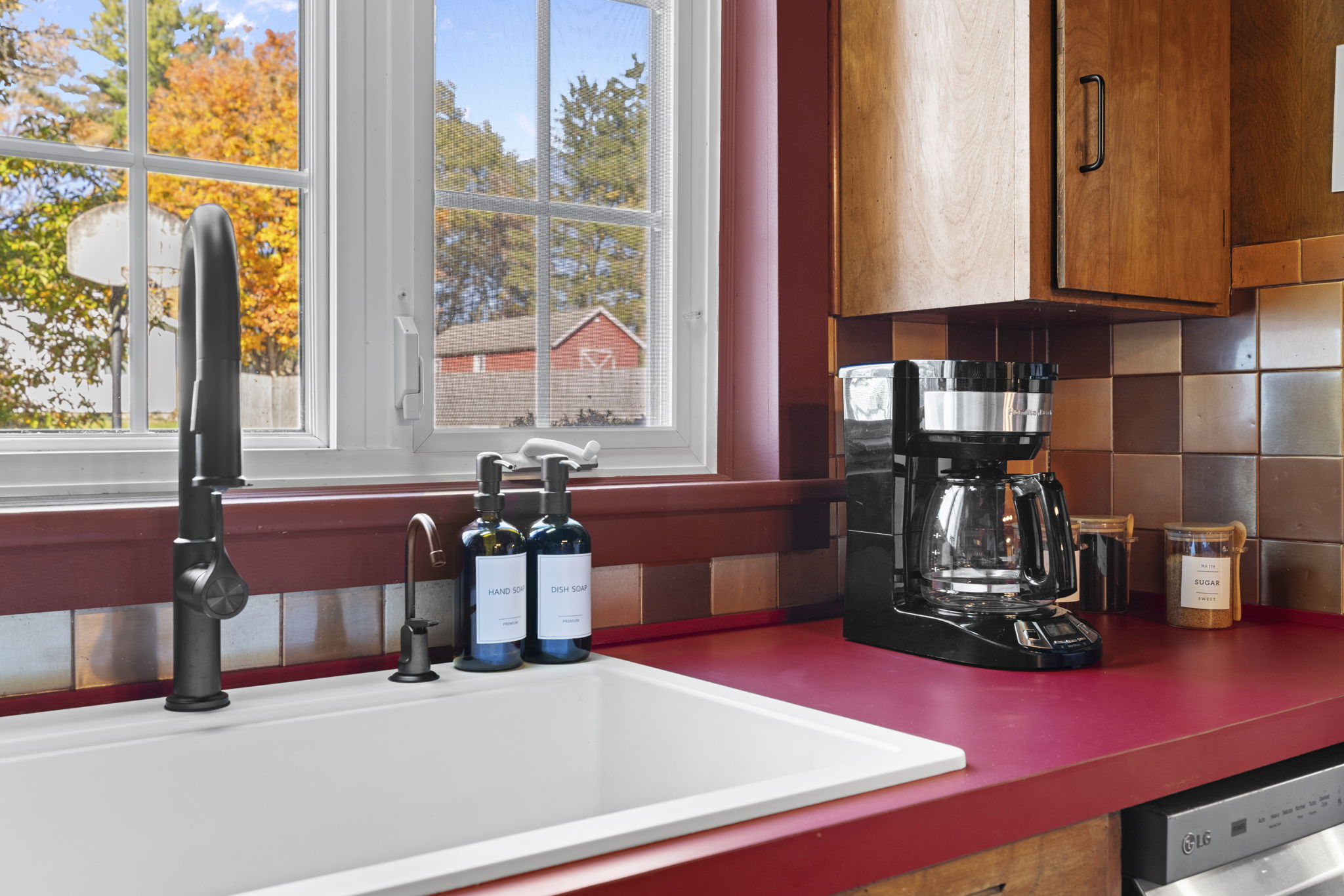 Sunny kitchen nook with farmhouse sink, coffee station, and fall views