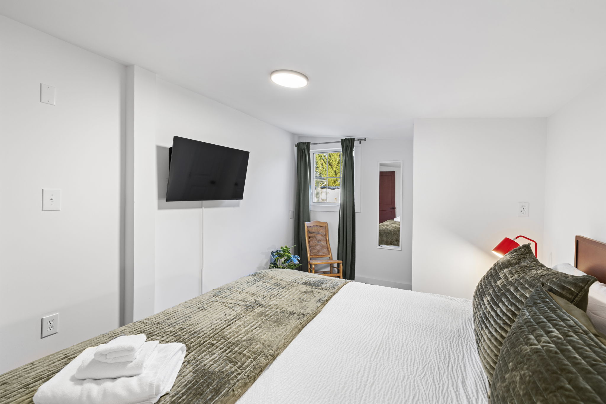 Bright, cozy bedroom with wall-mounted TV and clean modern styling