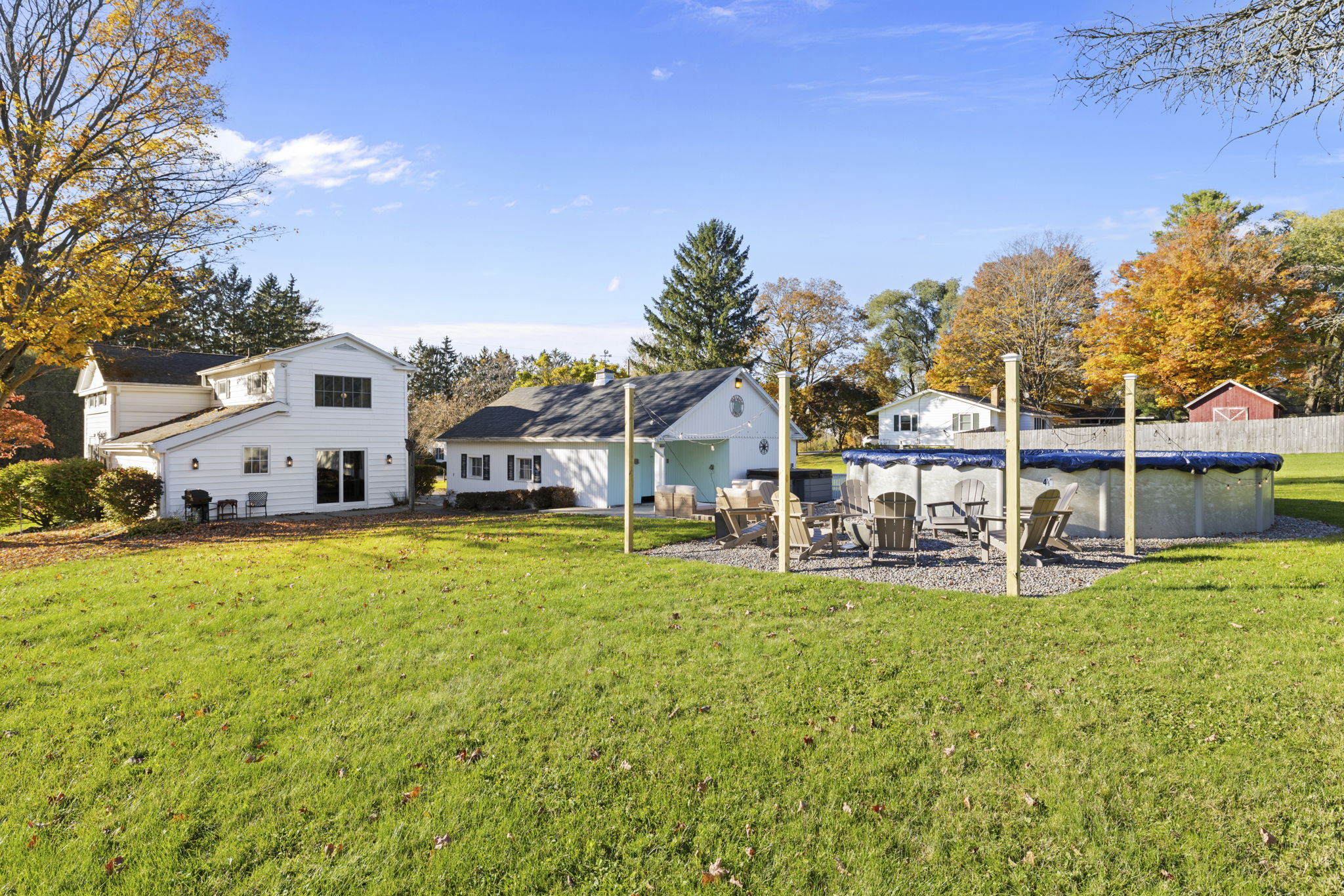 Spacious backyard with pool, patio seating, and beautiful fall scenery