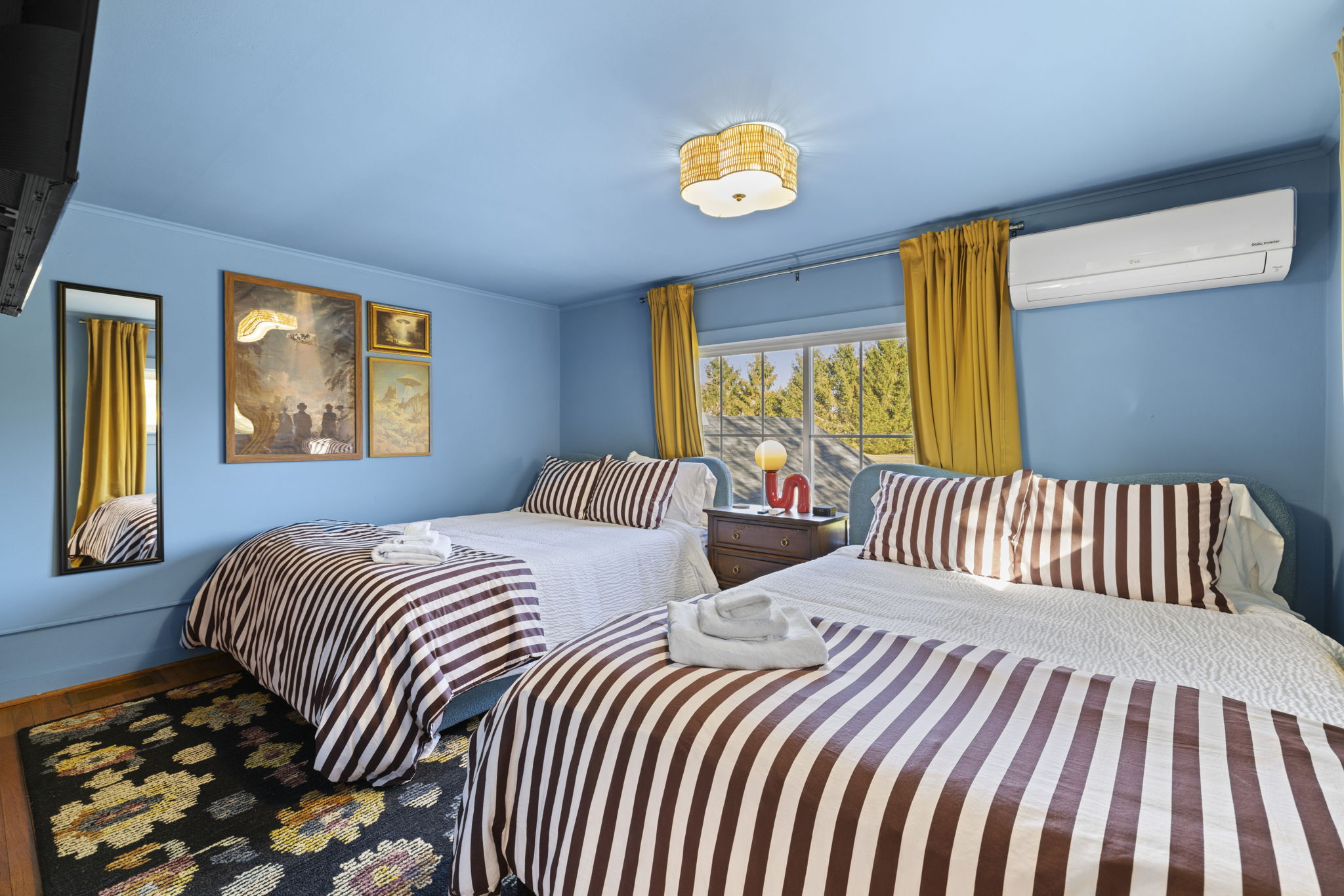 Bright double bedroom with two cozy beds, A/C, and sunny window views