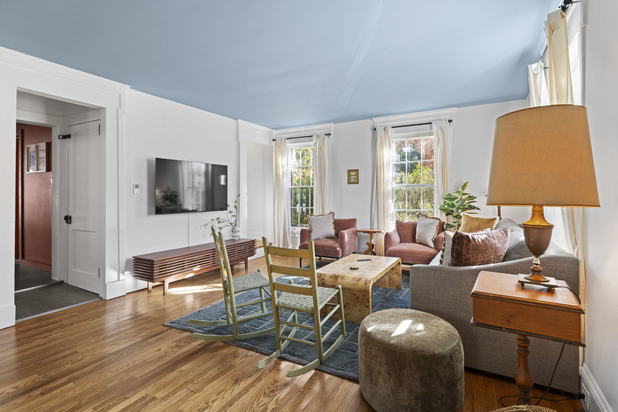 Sunlit living room with cozy seating, hardwood floors, and smart TV