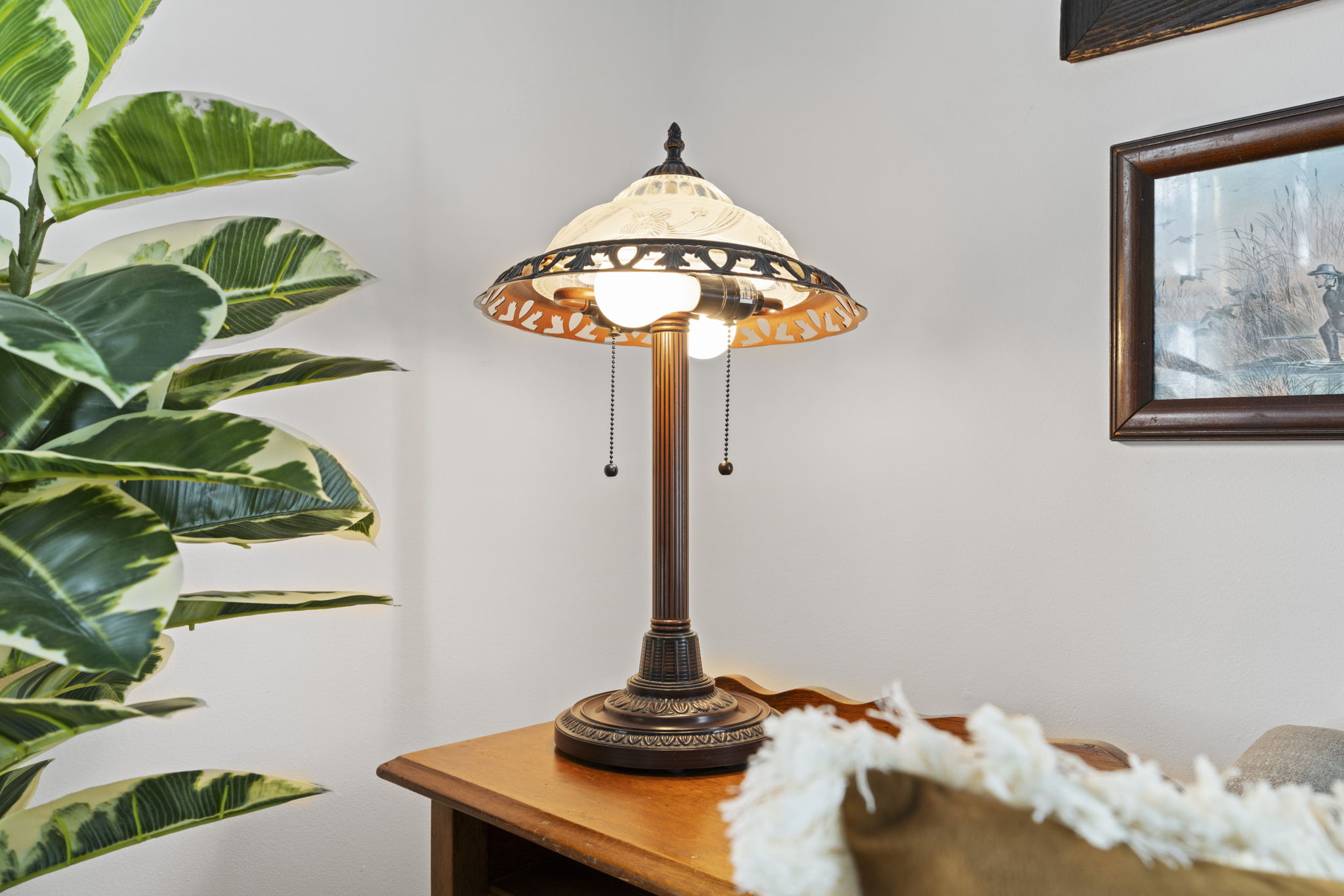 Cozy reading nook with vintage lamp, warm wood accents, and lush greenery