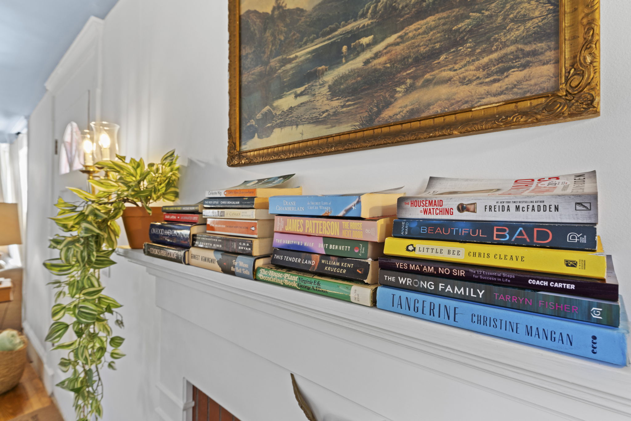 Cozy mantel styling with books, greenery, and timeless artwork