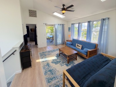 Bright vaulted living room with skylight, cozy seating, and deck access