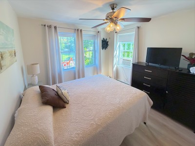 Bright, cozy bedroom with natural light, TV, and ceiling fan