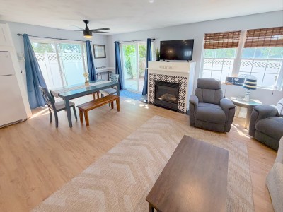 Bright living space with fireplace, TV, dining area, and patio access