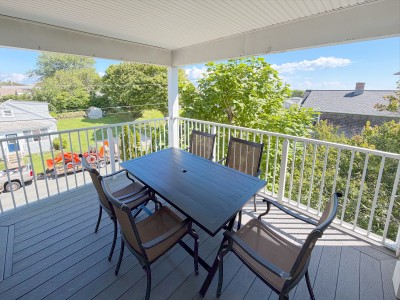 Covered balcony with outdoor dining and bright leafy neighborhood views