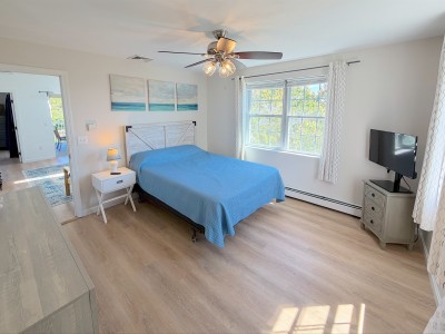 Bright and airy bedroom with coastal decor, large windows, and TV