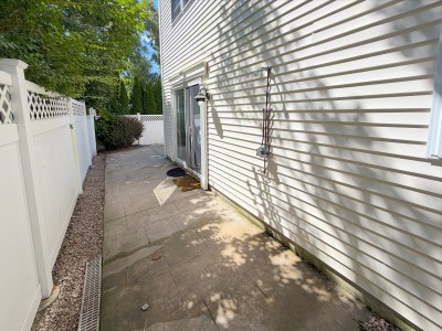 Private fenced side patio with paved walkway and outdoor entry
