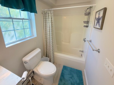 Bright full bath with natural light, tub-shower combo, and coastal touches