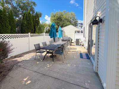 Private fenced patio with outdoor dining, umbrellas, and grill