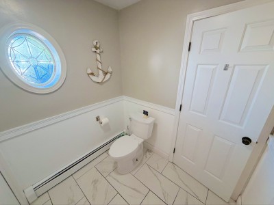 Bright coastal-style half bath with charming round window detail