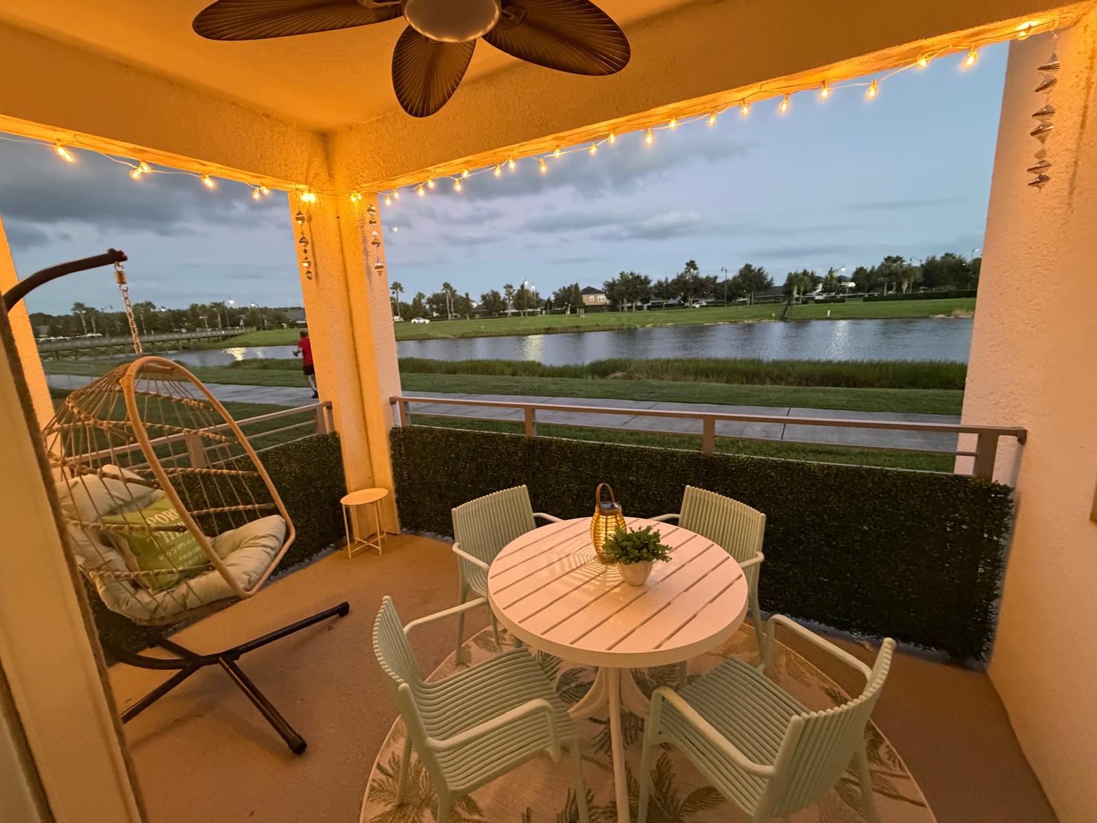 Cozy waterfront patio with string lights, dining set & relaxing egg chair