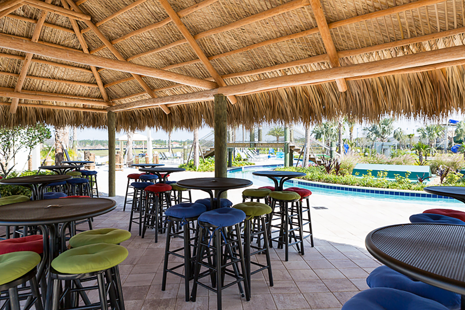 Tropical poolside palapa with colorful seating and relaxed open-air vibes