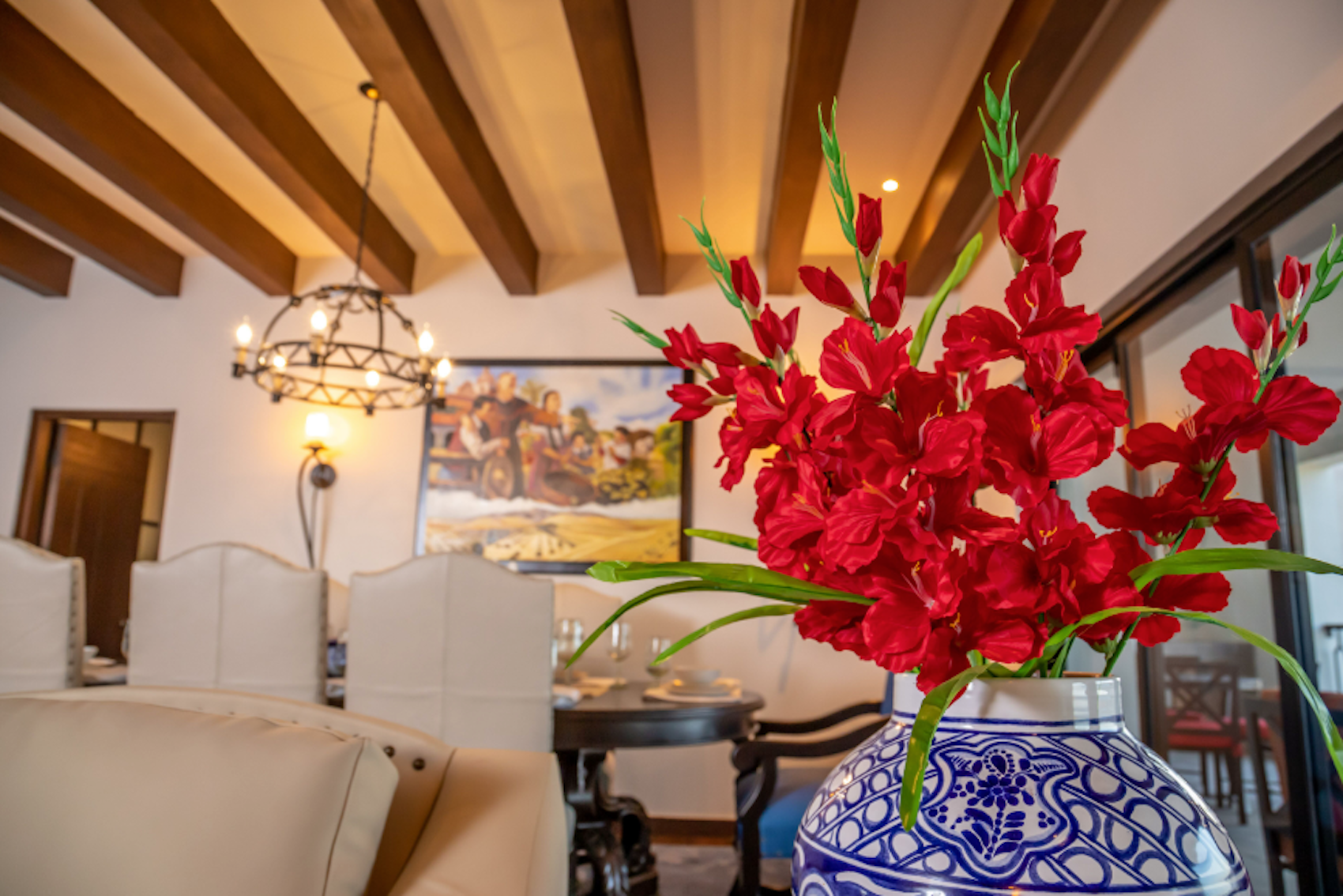 Elegant dining room with wood beams, chandelier, and vibrant floral accents