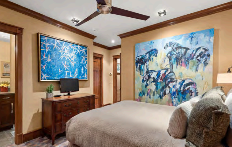 Cozy art-filled bedroom with plush bedding, TV, and ensuite access