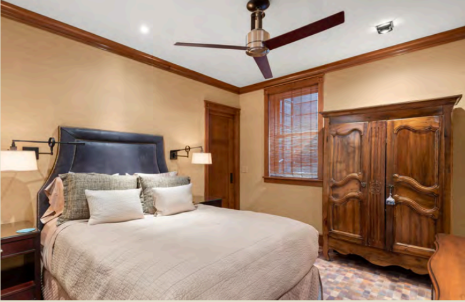 Cozy, elegant bedroom with plush bedding, wood details, and ceiling fan
