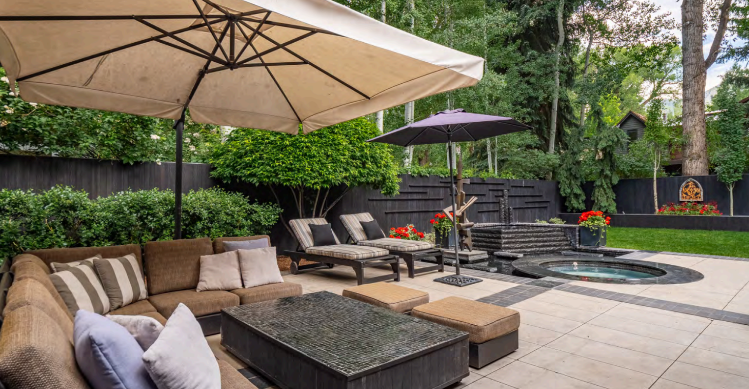 Private backyard oasis with hot tub, loungers, and shaded patio seating