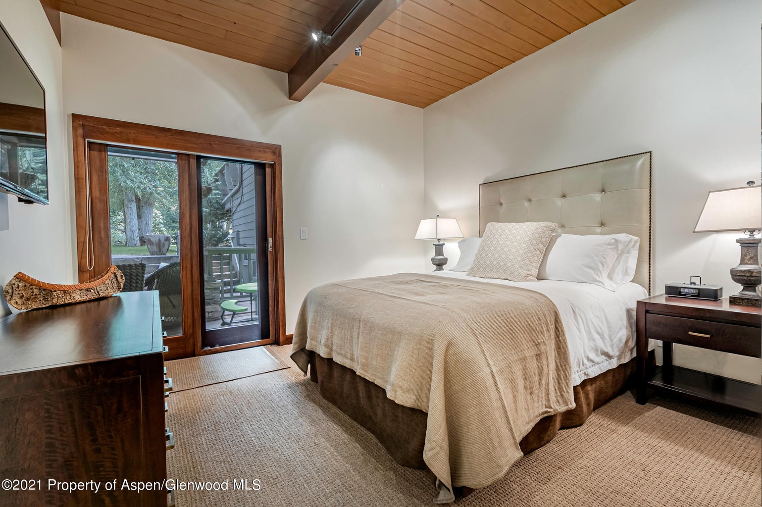Cozy vaulted bedroom with patio access and warm mountain-lodge charm