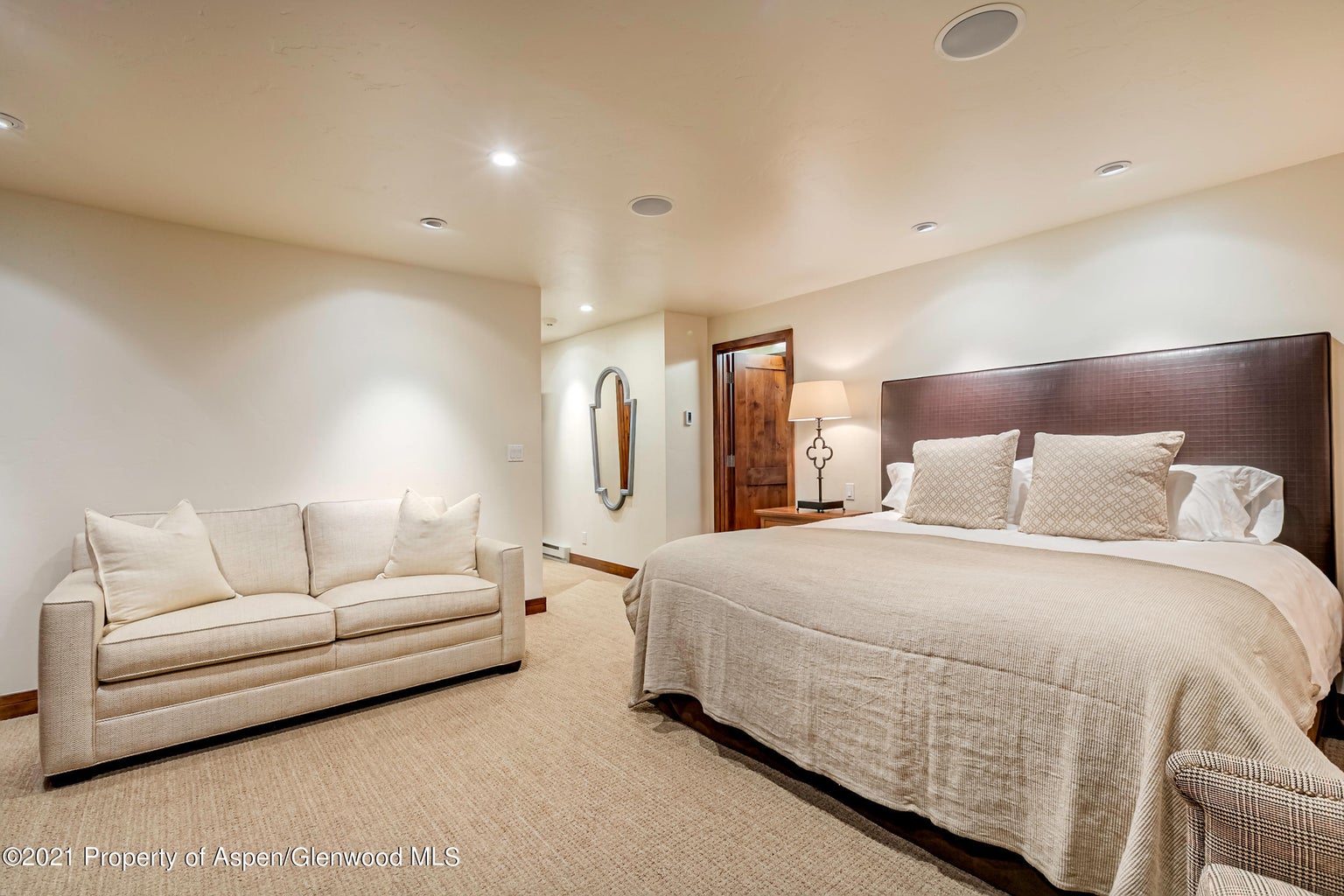 Spacious king bedroom with cozy sofa and warm, inviting design