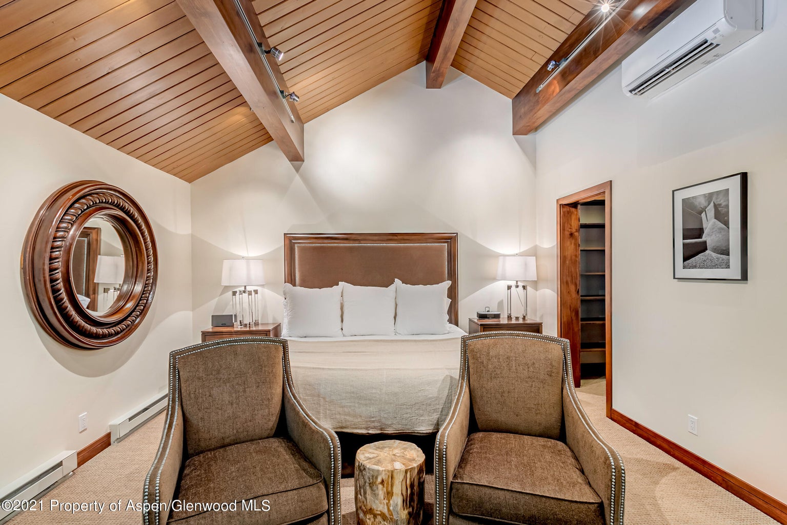 Cozy king bedroom with vaulted wood ceilings and inviting seating area