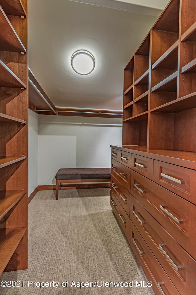 Spacious walk-in closet with custom built-ins, drawers, and bench seating