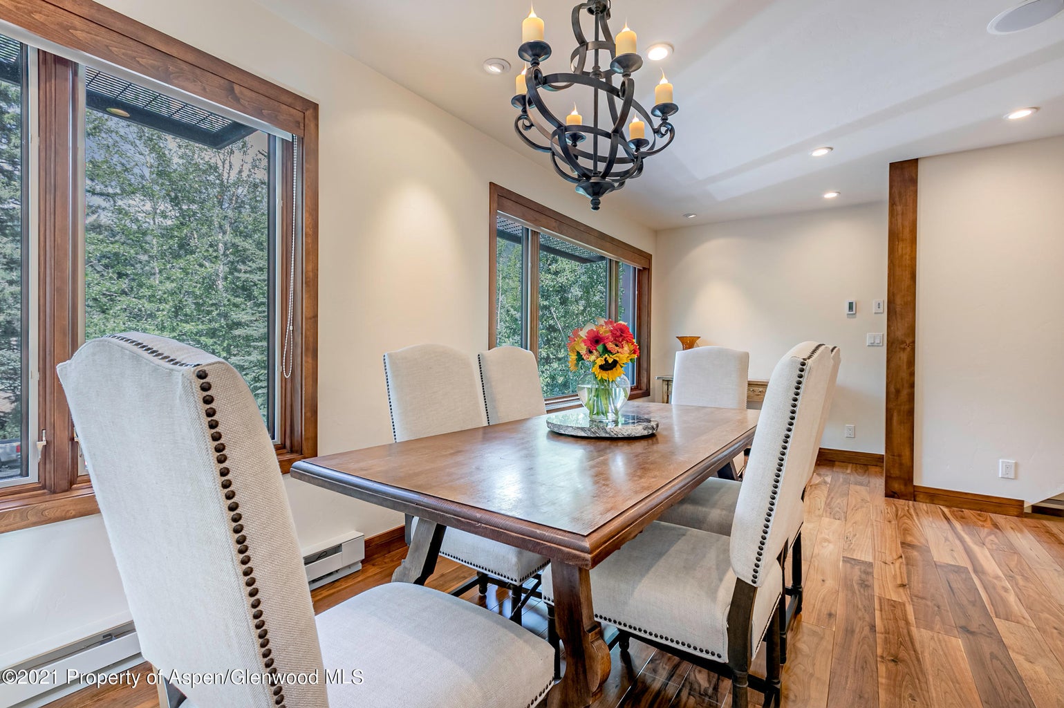 Bright dining room with tree views, elegant chandelier, and seating for six
