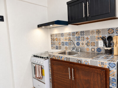 Charming tiled kitchen with gas stove, vent hood, and stylish storage