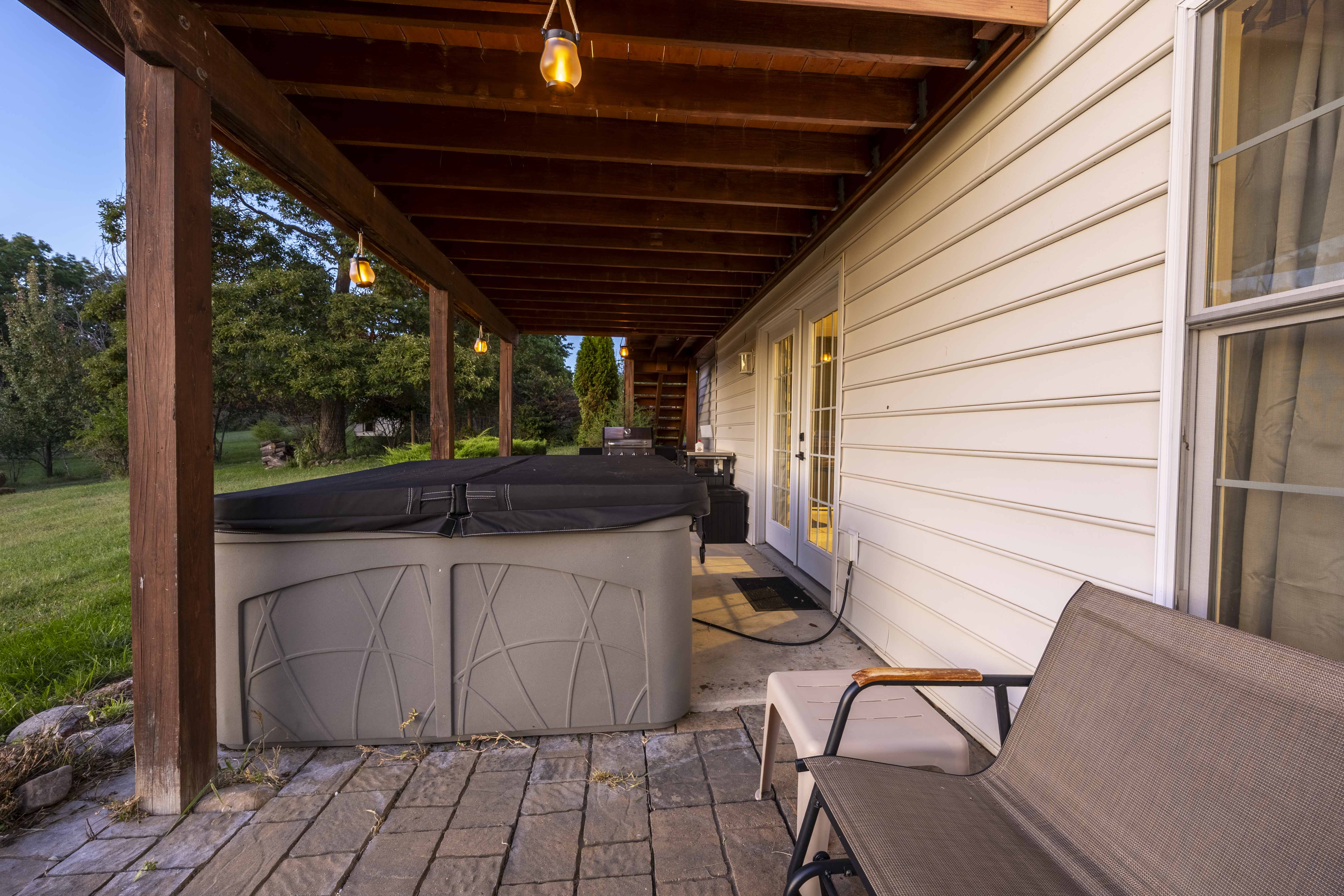 Covered patio with private hot tub and peaceful backyard views