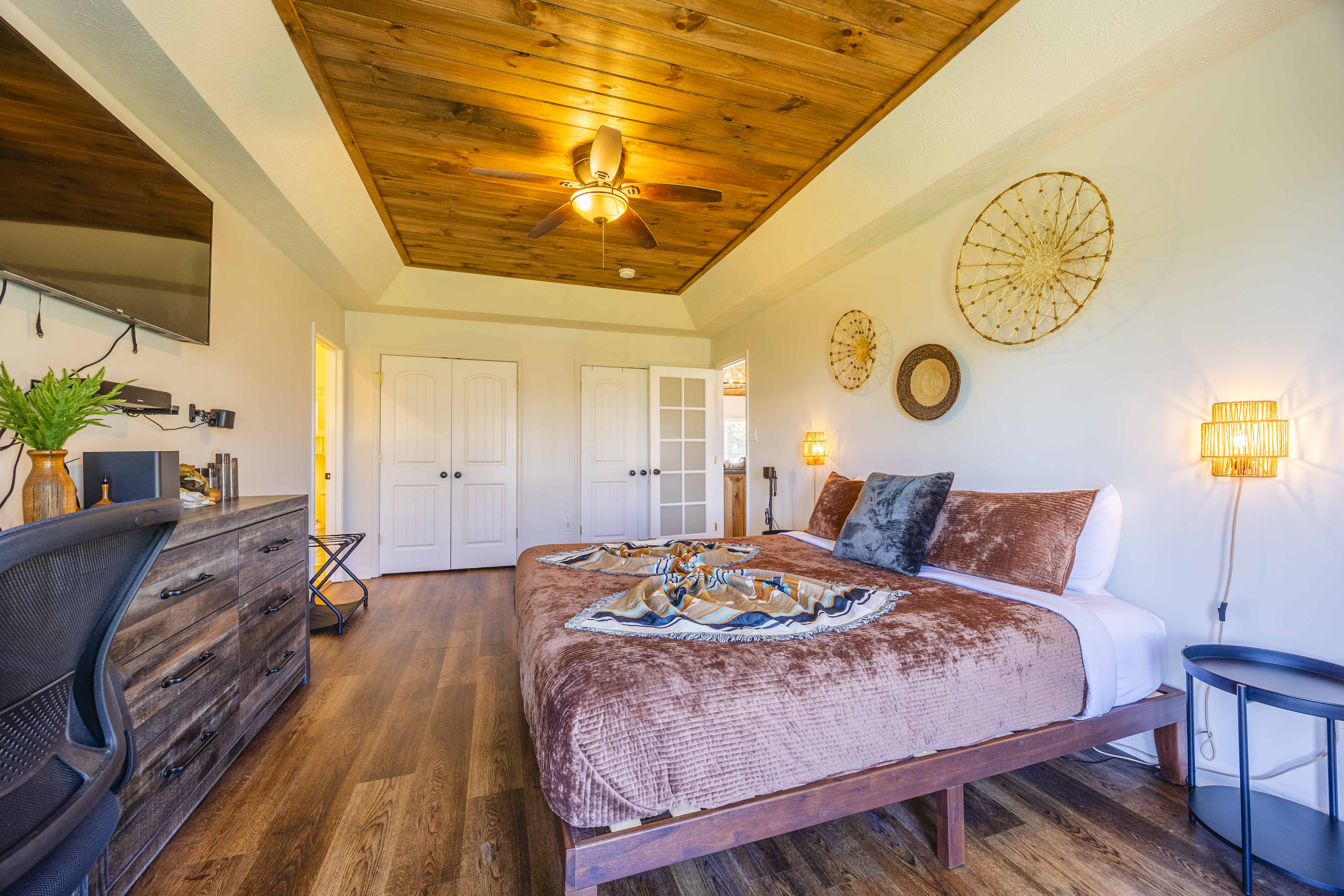 Spacious rustic bedroom with wood ceiling, workspace, and cozy king bed