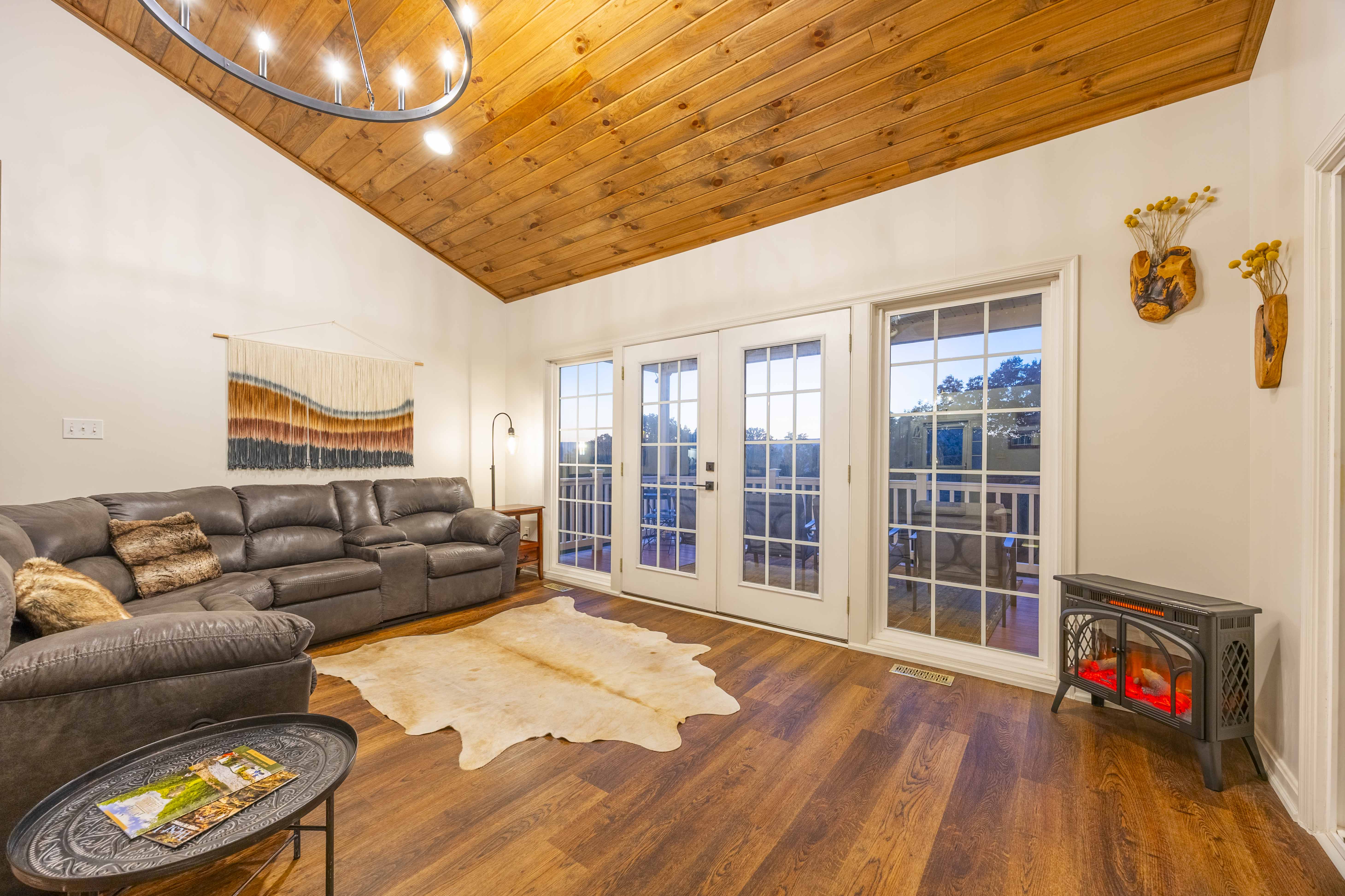 Cozy living room with vaulted wood ceilings, fireplace, and view deck access