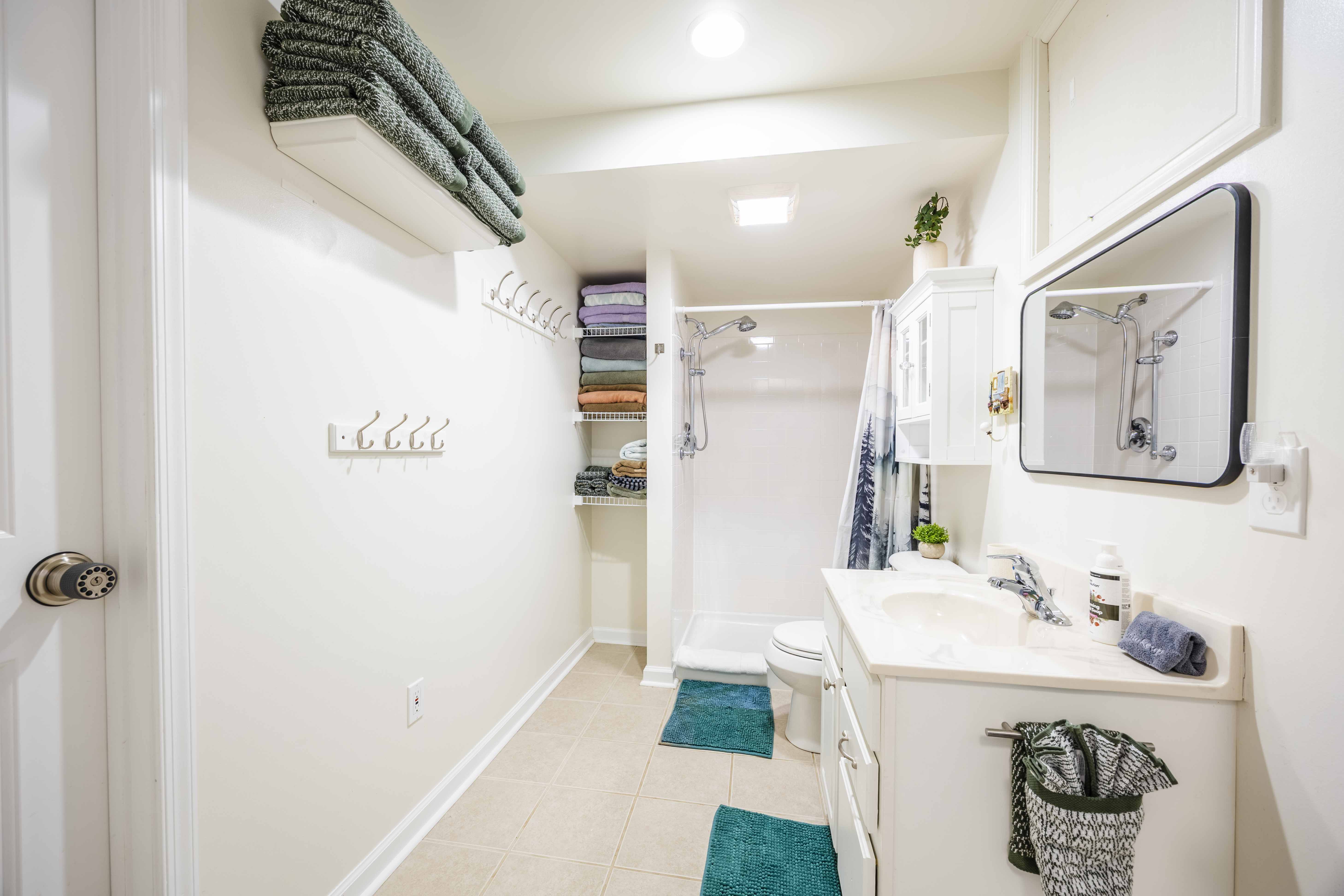 Bright bathroom with full shower, vanity, and plenty of fresh towel storage