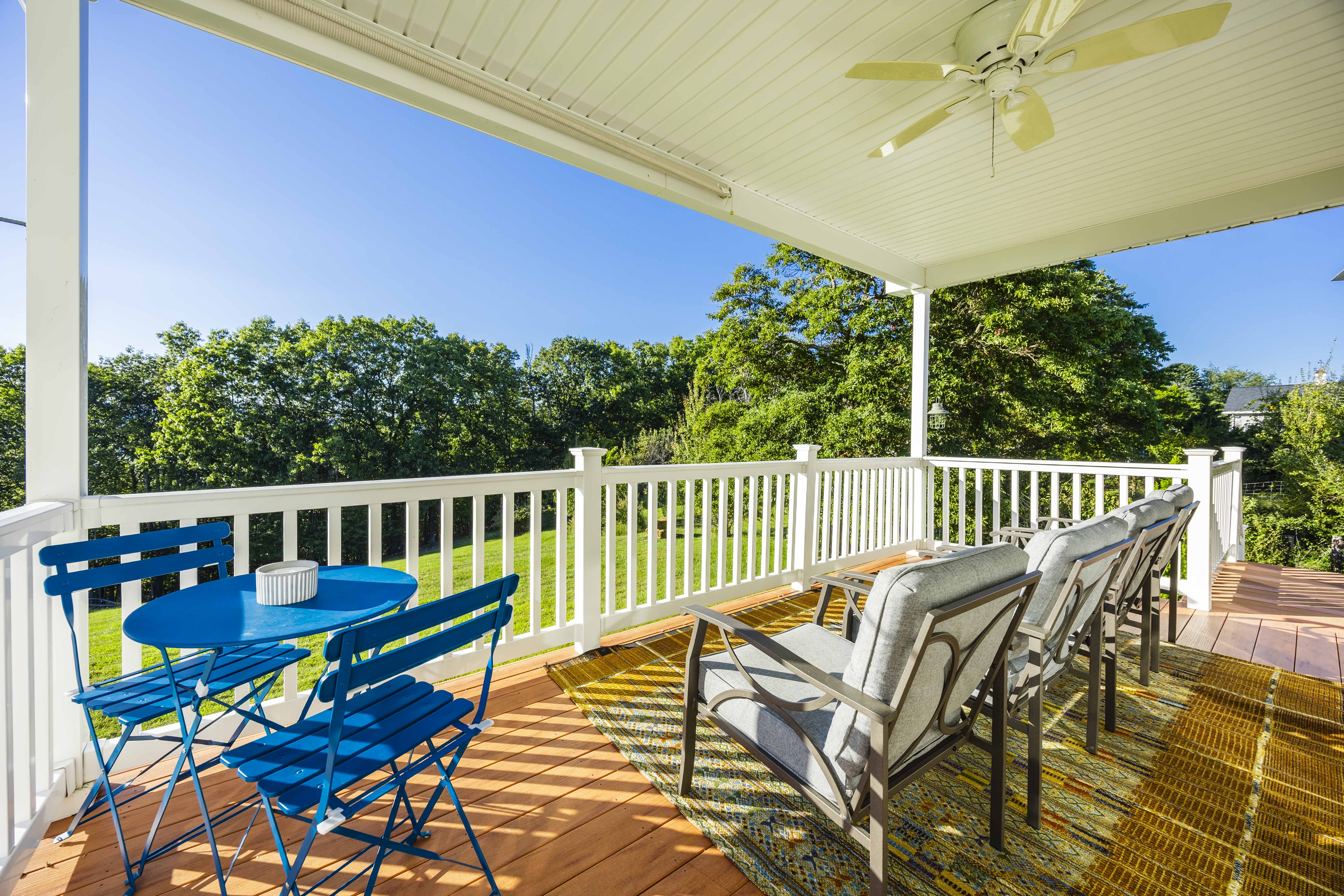Sunny covered deck with lounge seating and peaceful tree-lined views