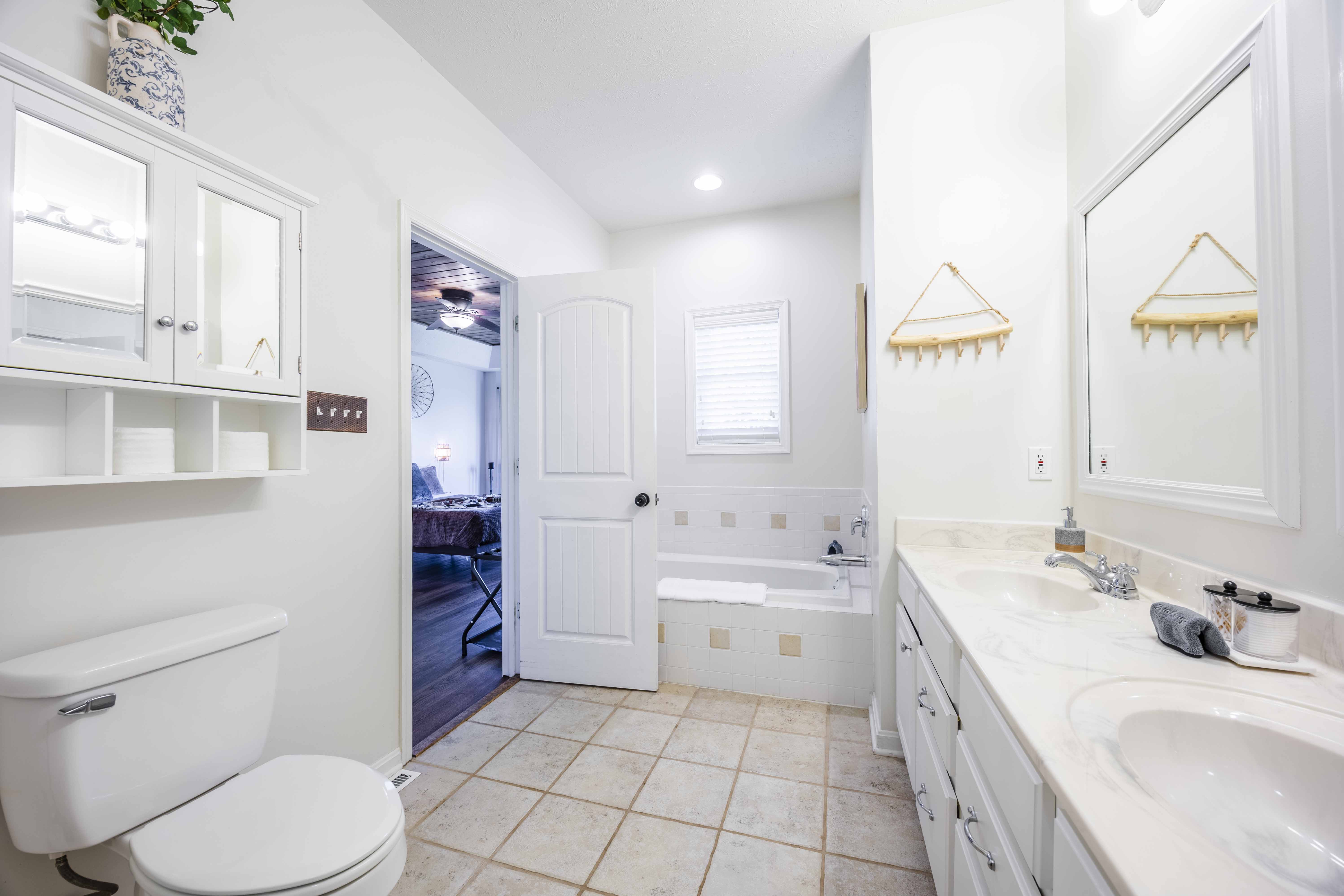 Bright bathroom with dual sinks, soaking tub, and spacious vanity