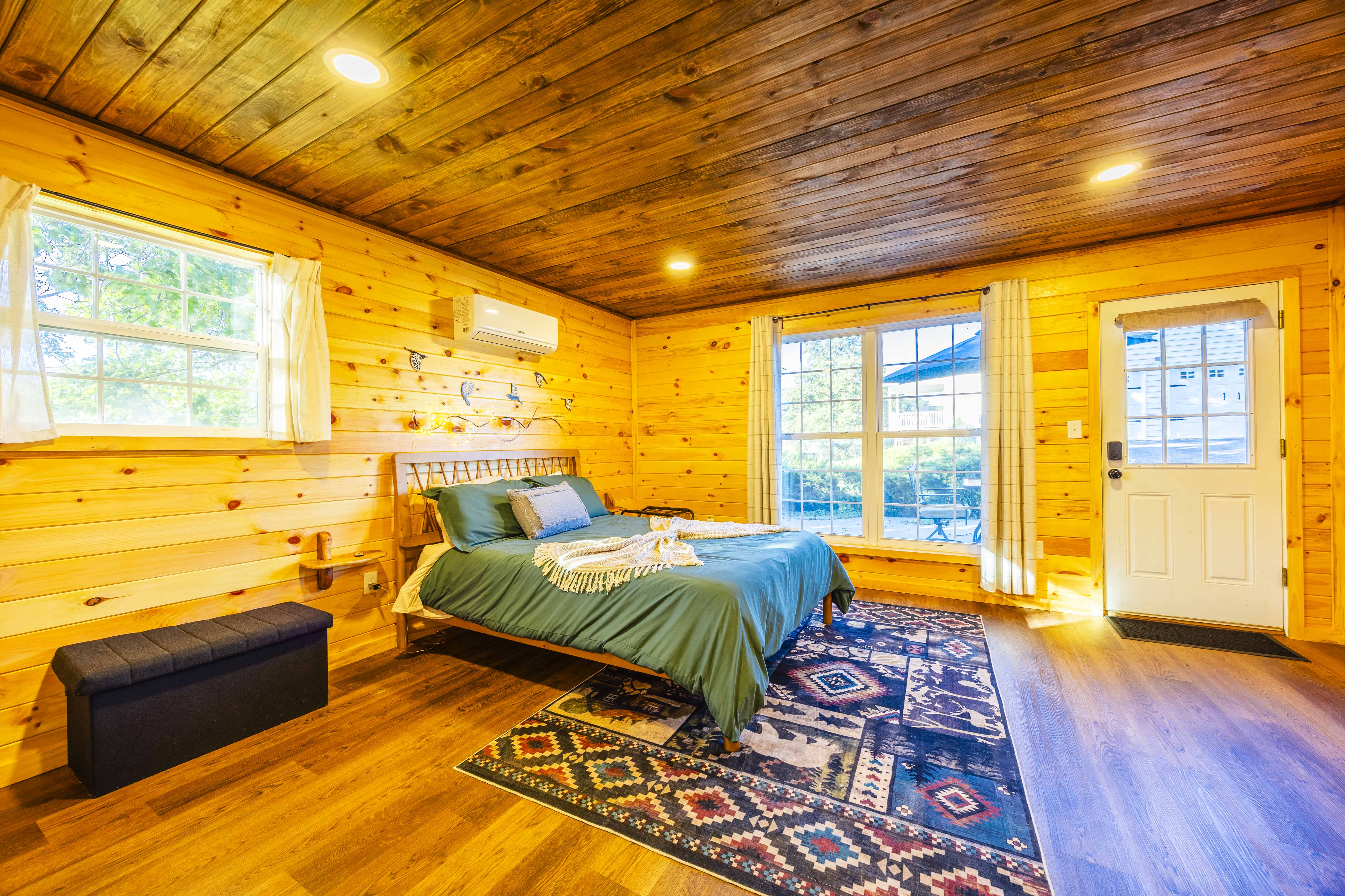 Cozy wood-paneled cabin bedroom with bright windows and rustic charm
