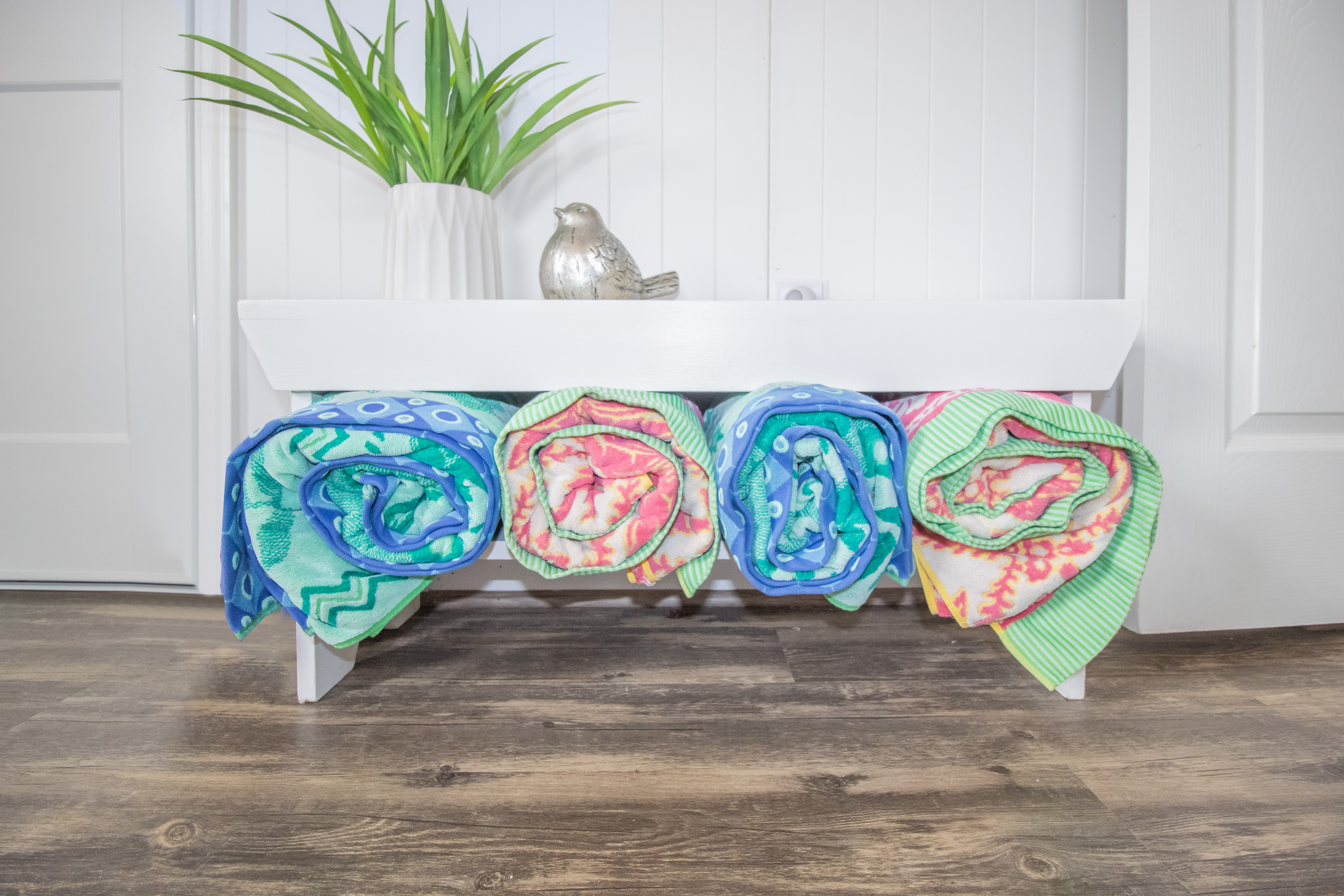Colorful beach towels neatly stocked beneath a bright, stylish bench