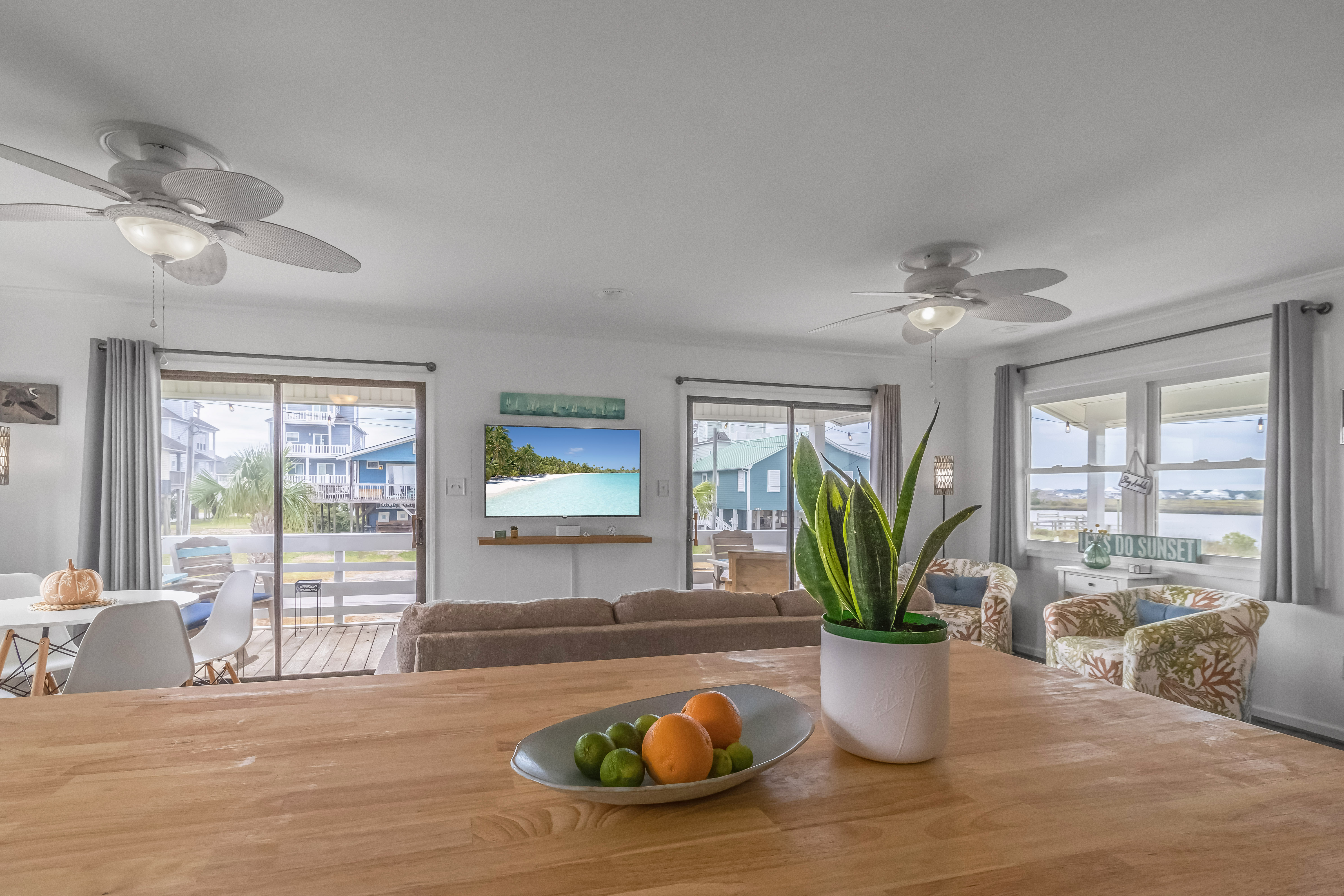 Bright coastal living space with deck access, big windows, and water views