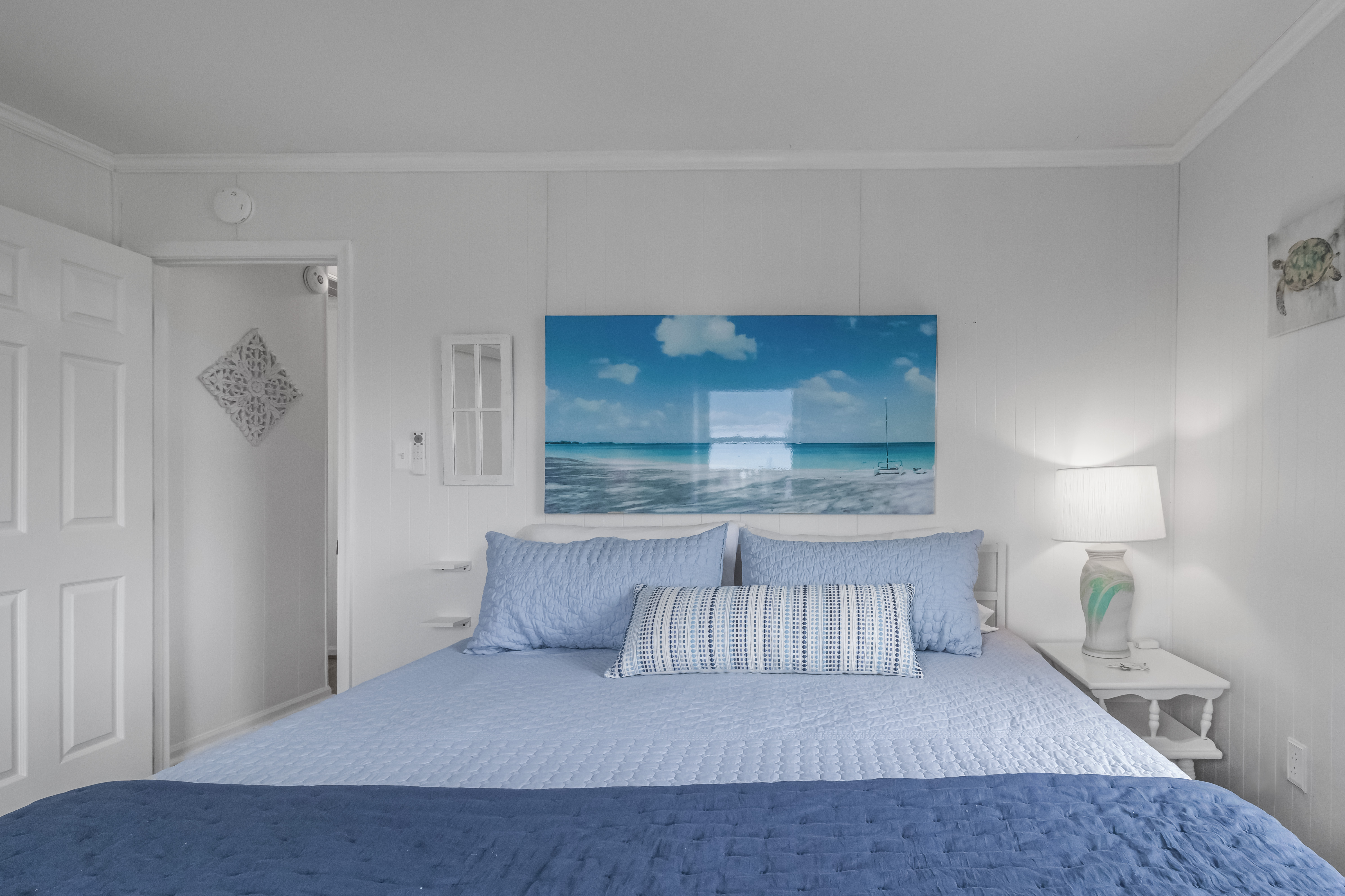 Coastal-inspired bedroom with plush king bed and serene beachy décor